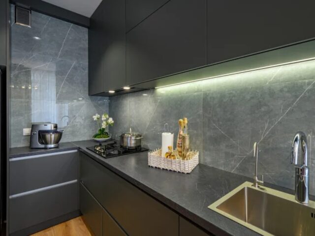 Dark kitchen cabinetry with marble backsplash and brass fittings