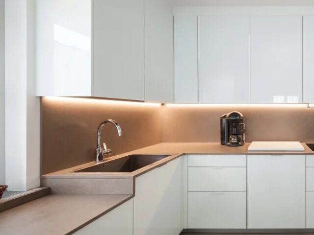 Minimal white kitchen with copper backsplash by Mastery Cabinetry