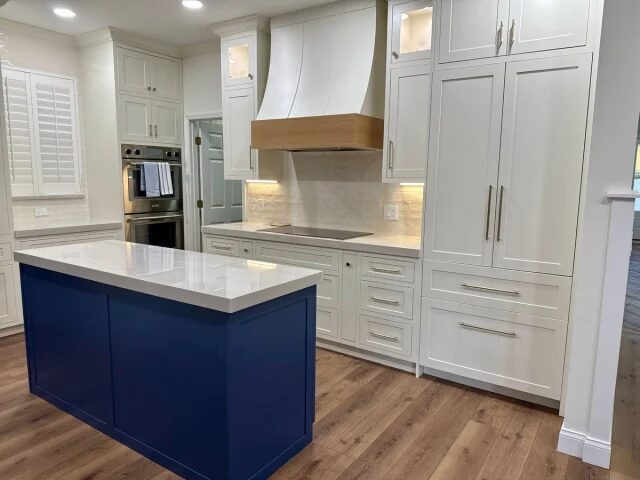 Navy island kitchen with a custom hood by Mastery Cabinetry