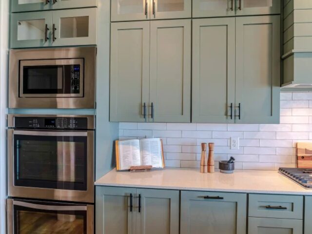 Sage green kitchen with double ovens by Mastery Cabinetry Orlando