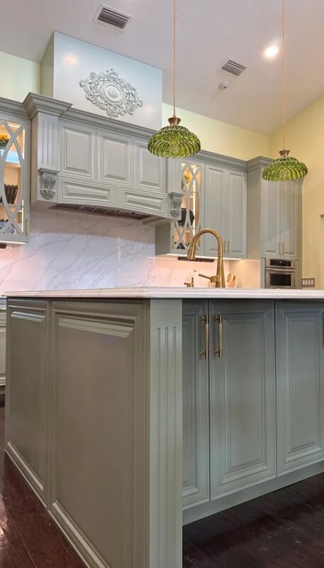 Sage kitchen island with glass pendants by Mastery Cabinetry