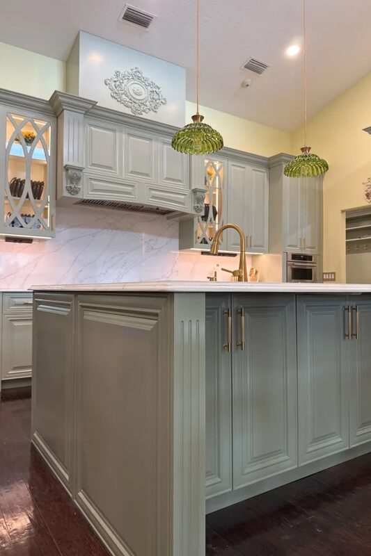 Sage kitchen island with glass pendants by Mastery Cabinetry