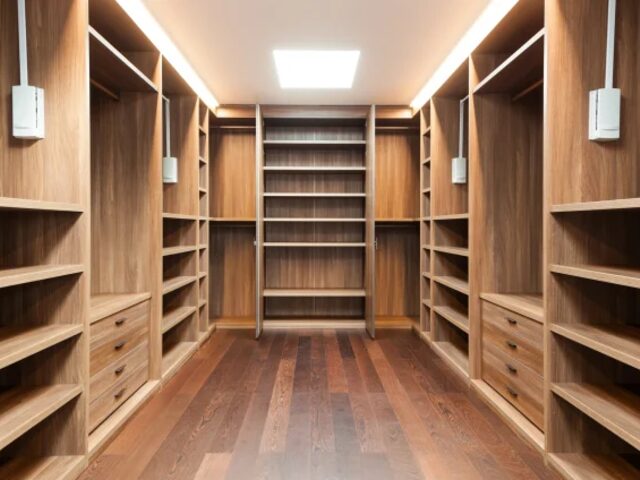 Custom walk in closet with walnut shelving by Mastery Cabinetry