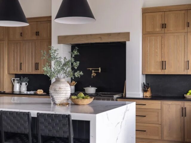 Walnut kitchen with black backsplash and stone island by Mastery Cabinetry